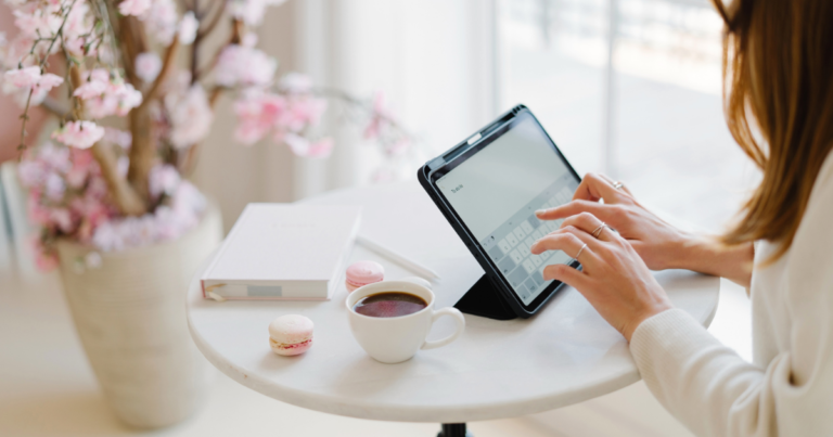 A woman in a soft pink jumper sitting cross-legged on a white bed with a mug of coffee, for a post on why you say yes before you've decided.